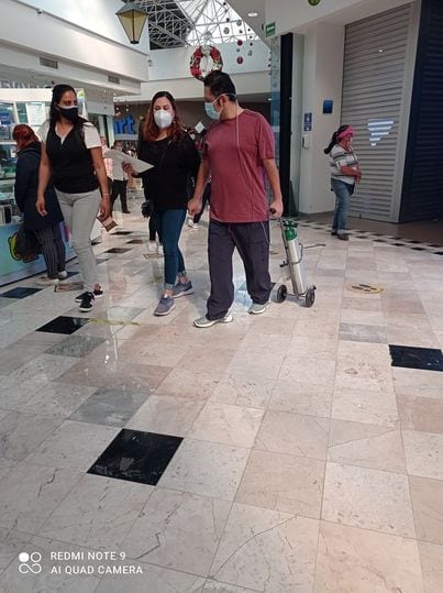 Una usuaria de redes sociales subió una imagen de dos mujeres y un hombre caminando por un centro comercial, mientras que él jala su tanque de oxígeno en medio de la pandemia de covid-19.